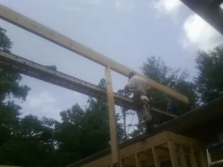 Carpenter setting a ridge beam over a new addition frame — Ice Dam Removal by Roofing Brothers in Bunnlevel