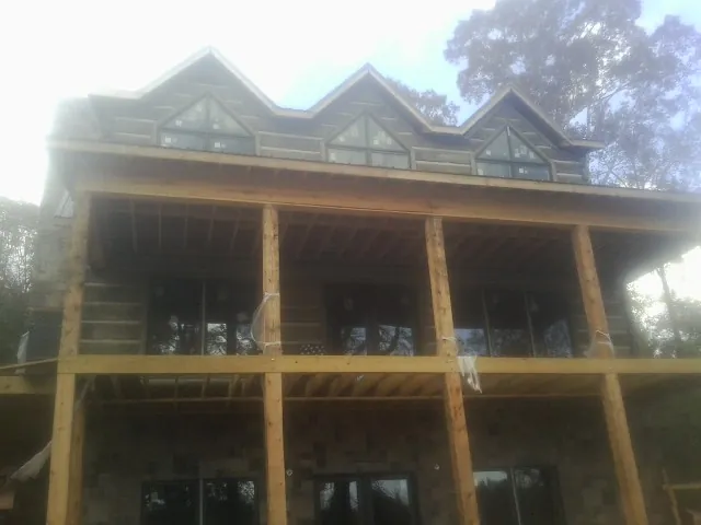 Dormers and porch framing on a large log home under construction — Roof Coating work by our crew in Bunnlevel